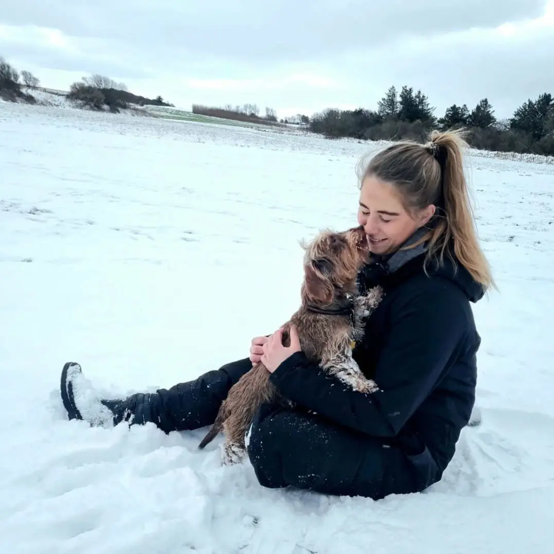 Kvinde leger med hund i sneen