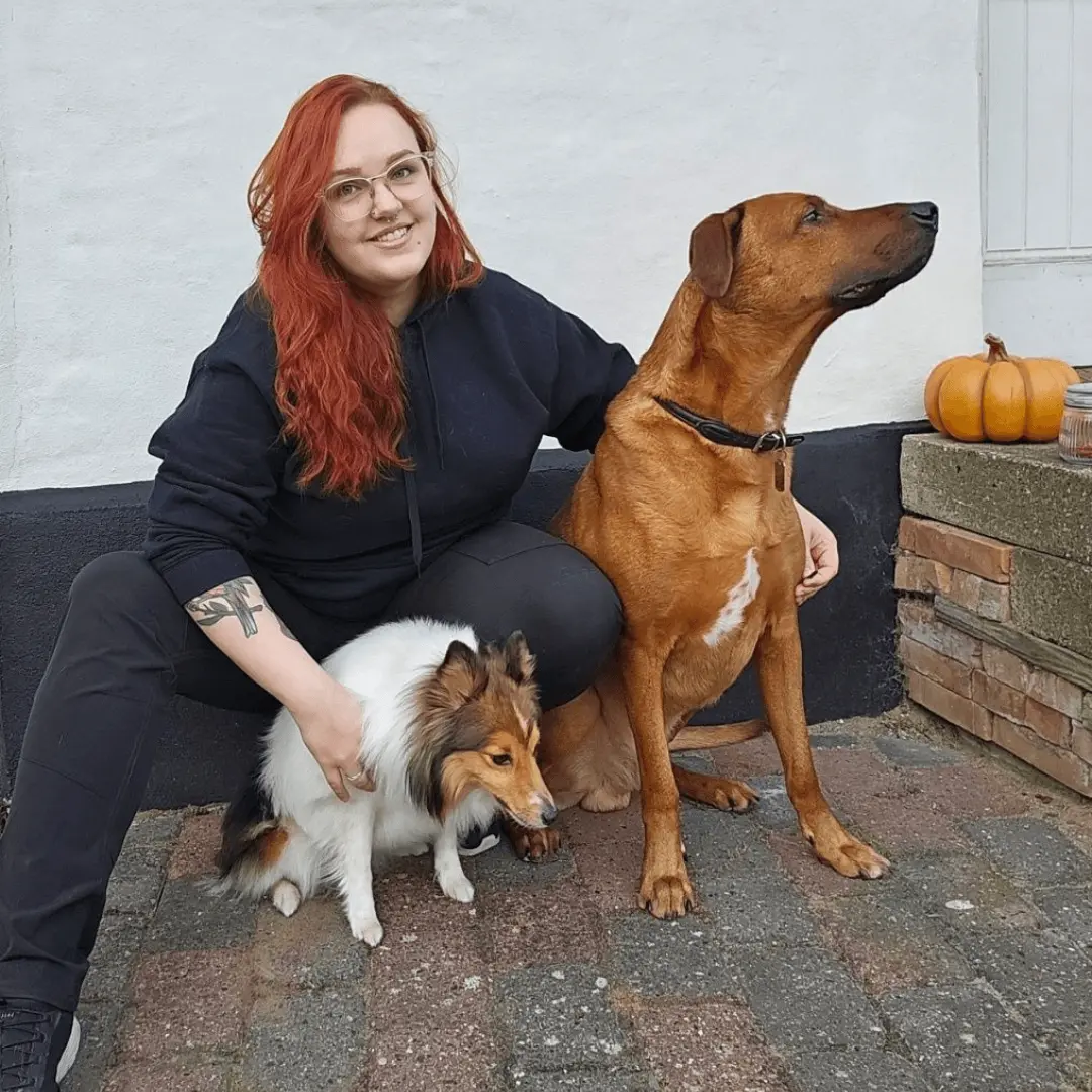 Person med to hunde foran et hus