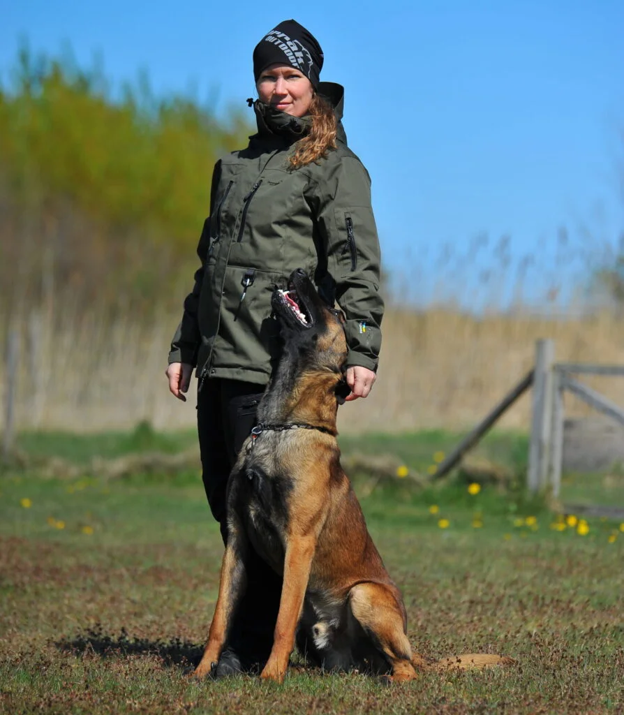 Kvinde træner sin hund udendørs på en mark