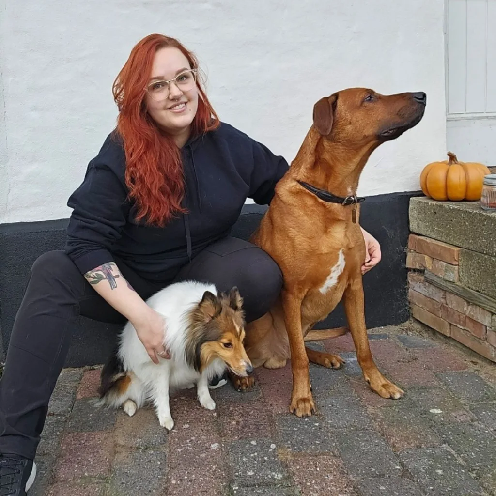 Person med to hunde foran et hus